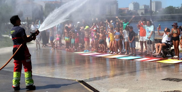 Un bombero mojando a
los concentrados por 
la esclerosis múltiple, ayer, 
en Bouzas. |  J. Lores