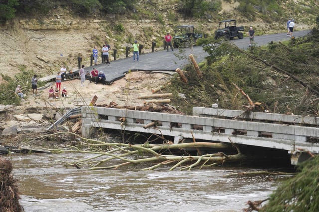 People wait Saturday on the other side of a bridge that crosses the Guadalupe River after heavy rainfall in Central Texas damaged the structure and stranded several homes without power or aid.