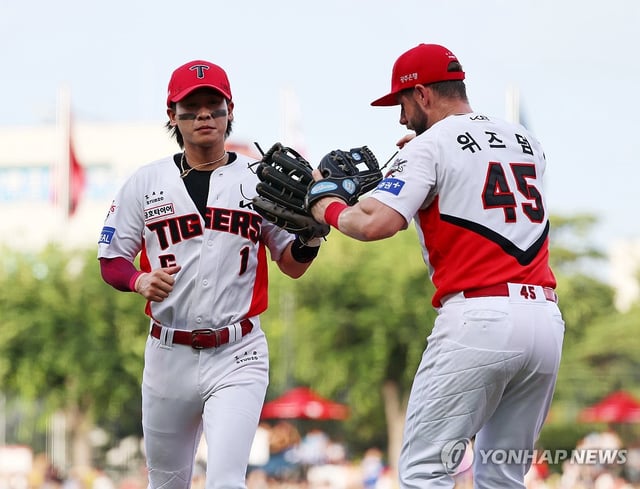 Kia Tigers shortstop Park Chan-ho (L) is greeted by teammate Patrick Wisdom after turning a double play against the Lotte Giants during the clubs' Korea Baseball Organization regular-season game at Gwangju-Kia Champions Field in Gwangju, 270 kilometers south of Seoul, on July 6, 2025. (Yonhap)