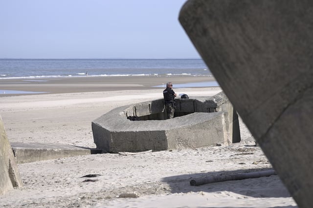 A gendarme stands in a WWII nazi bunker at Ecault beach, Friday July 4, 2025. (AP Photo/John Leicester)