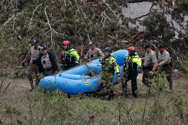 Members from Texas Game Wardens of the Law Enforcement Divison and rescuers carry an inflatable boat after pulling it out of the river, following flash flooding, in Kerrville, Texas, U.S. July 6, 2025. REUTERS/Marco Bello