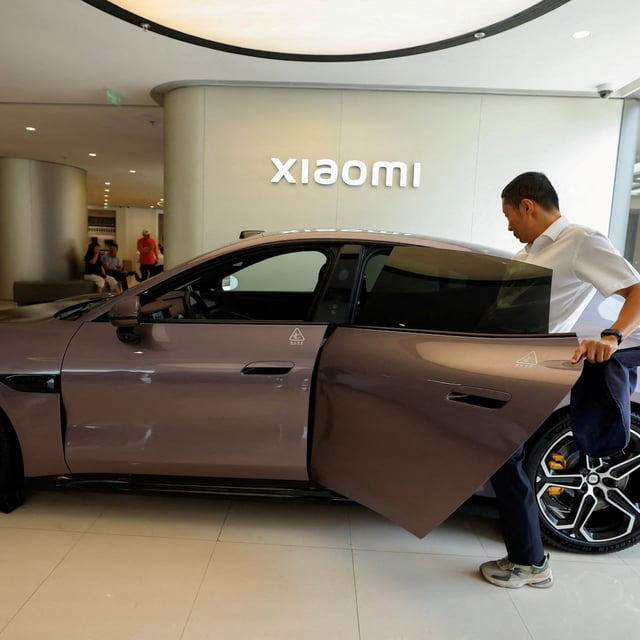 FILE PHOTO: A person tries the electric sedan SU7 displayed at a Xiaomi store in Beijing, China May 29, 2025. REUTERS/Tingshu Wang/File Photo