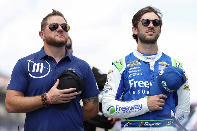 Daniel Suarez, driver of the #99 Freeway Insurance Chevrolet, (R) and Trackhouse Racing team co-owner Justin Marks stand on the grid during pre-race ceremonies prior to the NASCAR Cup Series Verizon 200 at the Brickyard at Indianapolis Motor Speedway on July 31, 2022 in Indianapolis, Indiana.