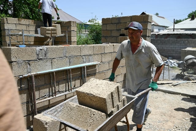 Des ouvriers construisent une maison avec des parpaings en riz, dans le village de Kyzyl-Kiya, dans le sud du Kirghizistan, le 22 mai 2025