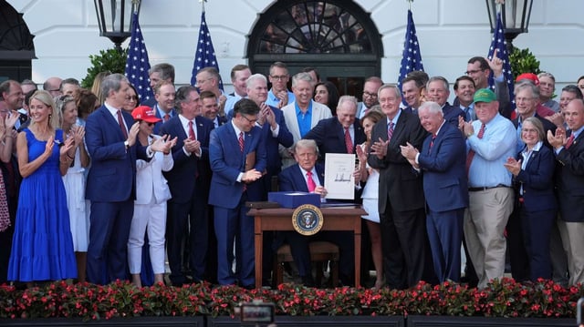U.S. President Donald Trump holds up his signed spending and tax cut legislation surrounded by members of Congress, at the White House, in Washington, July 4, 2025 (AP photo by Julia Demaree Nikhinson).
