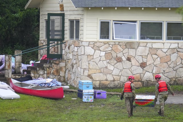 Military personnel return a camp trunk salvaged from down river to Camp Mystic along the Guadalupe River after a flash flood swept through the area Sunday, July 6, 2025, in Hunt, Texas. (AP Photo/Julio Cortez)