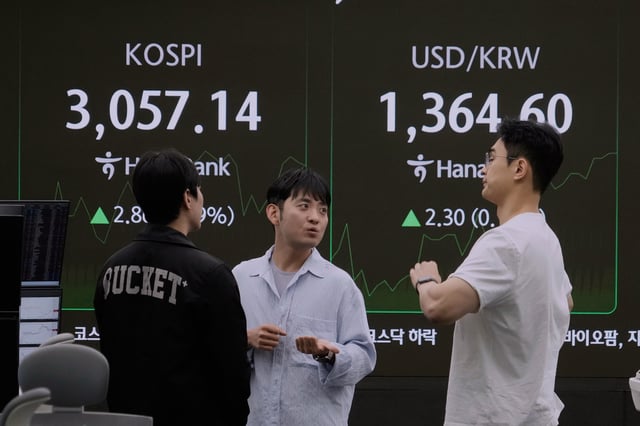 Currency traders work near a screen showing the Korea Composite Stock Price Index (KOSPI), top left, and the foreign exchange rate between U.S. dollar and South Korean won at the foreign exchange dealing room of the KEB Hana Bank headquarters in Seoul, South Korea, Monday, July 7, 2025. 