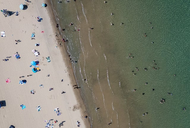 People relax on the sand and wade into the Lake Michigan water, June 22, 2025, at 57th Street Beach while the heat index soared above 100 degrees for the second straight day. (Brian Cassella/Chicago Tribune)