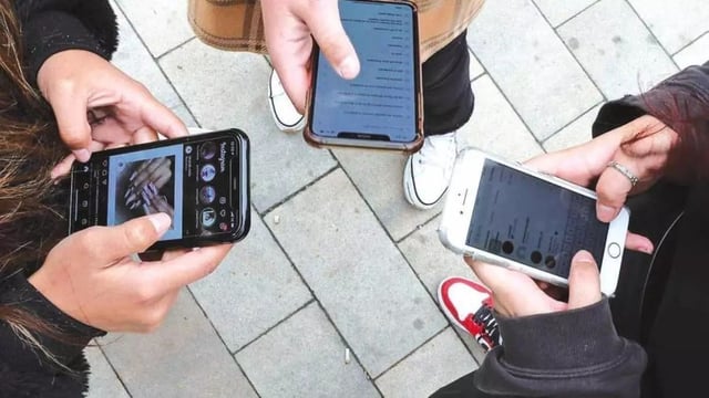 Jóvenes utilizan su móvil para navegar en redes sociales