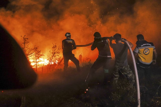 Emergency responders with the Syrian Civil Defense, known as the White Helmets, work to extinguish a wildfire near the town of Rabia, in Syria's Latakia countryside, early Monday, July 7, 2025. (AP Photo/Ghaith Alsayed)