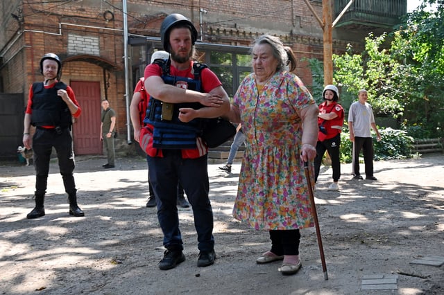 A Ukrainian medic helps a woman leave the site of a drone attack in Kharkiv on July 7, 2025, amid the Russian invasion of Ukraine.
