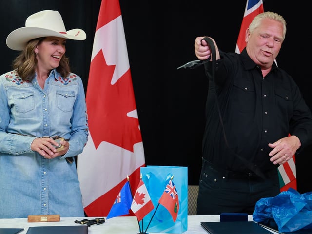  Alberta Premier Danielle Smith laughs as Ontario Premier Doug Ford whips off his belt to try out a belt buckle gift after the two signed new memorandums of understanding on energy, trade and interprovincial cooperation at McDougall Centre in Calgary on Monday, July 7, 2025.
