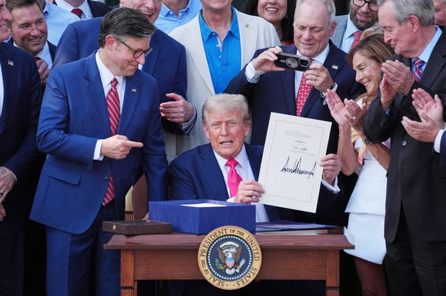 President Donald Trump signs his signature bill of tax breaks and spending cuts at the White House, Friday, July 4, 2025 surrounded by members of Congress.