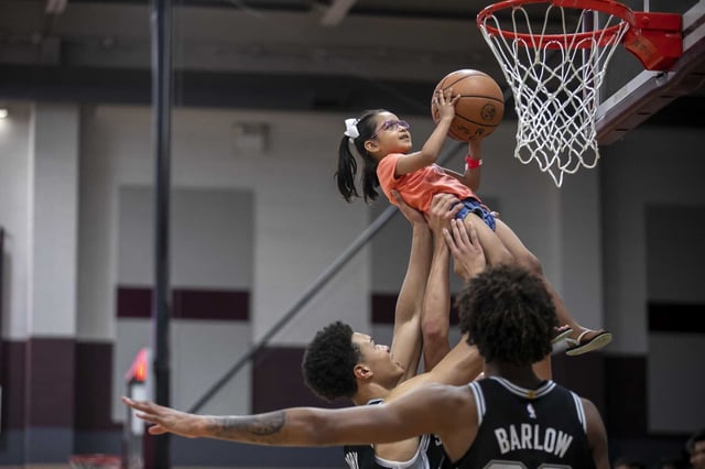 Players lift up a student to make a basket during a Spurs’ practice held at Uvalde High School&#39;s Harvey Kinchlow Gym in Uvalde, Texas, on Oct. 8, 2022 in the wake of the mass shooting at Robb Elementary School in May 2022. The Spurs are now seeking to help flood victims in the Hill Country.