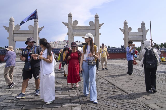 A tour guide chats with a tourist as they tour the Temple of Heaven, in Beijing on June 15, 2025. (AP Photo/Andy Wong)