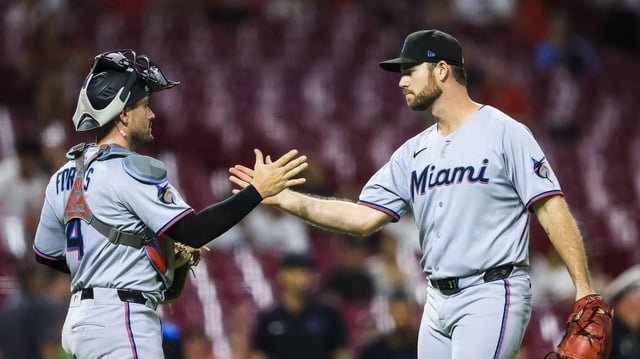 Miami’s Anthony Bender celebrates with catcher Nick Fortes after finishing off a 5-1 victory over the Reds on Monday.