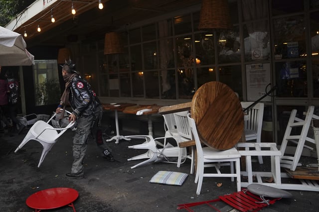 A demonstrator tosses a restaurant chair at the end of peaceful protest that turned violent against gentrification, as the increase in remote workers has risen prices and increased housing demand in neighborhoods like Condesa and Roma, in Mexico City, Friday, July 4, 2025. (AP Photo/Aurea Del Rosario)