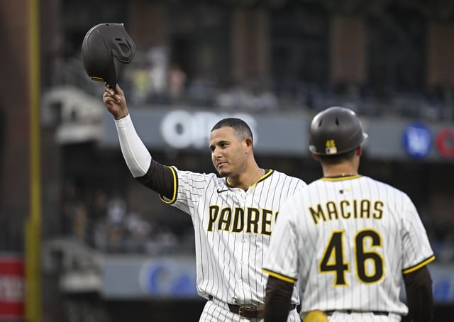 Jul 7, 2025; San Diego, California, USA; San Diego Padres third baseman Manny Machado (13) acknowledges the crowd after getting his 2000th career hit as first base coach David Macias (46) looks on during the fourth inning against the Arizona Diamondbacks at Petco Park. Mandatory Credit: Denis Poroy-Imagn Images