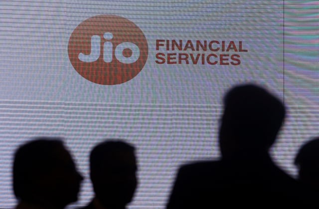 People stand next to a logo of Jio Financial Services ahead of its listing ceremony at the Bombay Stock Exchange in Mumbai, India, August 21, 2023. REUTERS/Francis Mascarenhas/File Photo