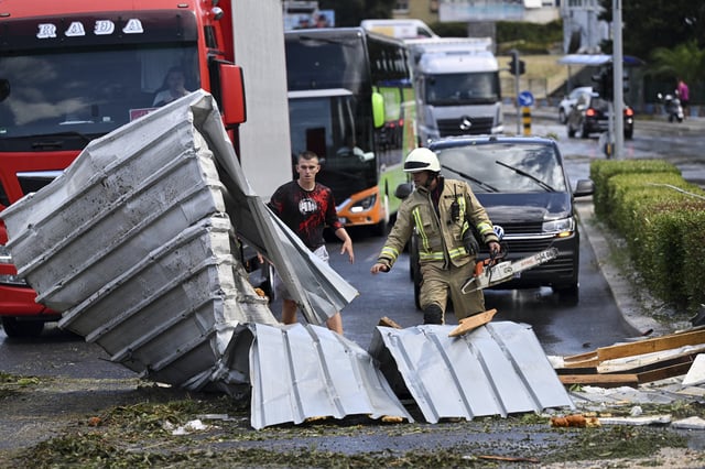 A fireman removes debris from a street in Split, Croatia, Tuesday, July 8, 2025, following a powerful storm. (AP Photo/Tom Dubravec)