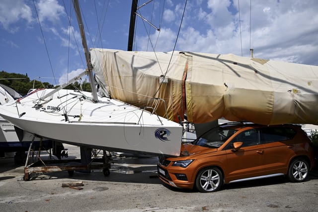 A car and boats are damaged in Split, Croatia, Tuesday, July 8, 2025, following a powerful storm. (AP Photo/Tom Dubravec)
