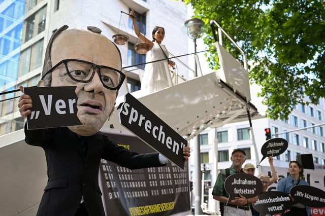An activist depicting Chancellor Friedrich Merz shows a broken "promise" lettering in a symbolic protest action for the continuation of visa issuance under the admission programs for vulnerable Afghans, in connection with the first wave of lawsuits against the Federal Foreign Office and the suspending and reassess all refugee programs of the German government, in Berlin, Germany June 20, 2025. REUTERS/Annegret Hilse/File Photo