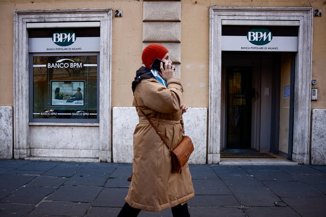 A woman talks on a mobile phone as she walks past a Banca Popolare di Milano (BPM) branch in Rome, Italy, December 17, 2024. REUTERS/Guglielmo Mangiapane/File Photo