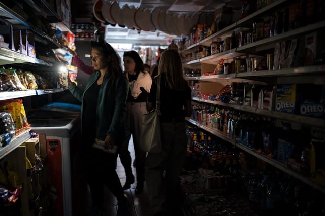 People shop for groceries using their phone as flashlight during a widespread power outage that struck Spain and Portugal in April (Photo by Diego Radames/Anadolu)