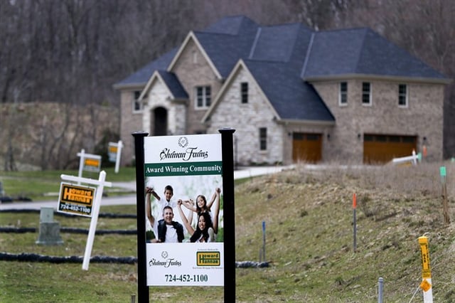 A listing sign for a house for sale is seen in a yard, surrounded by other sale signs.