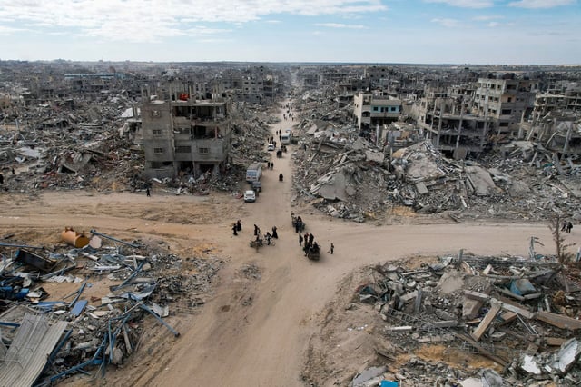 People make their way past the rubble of houses in Rafah on January 20, 2025.