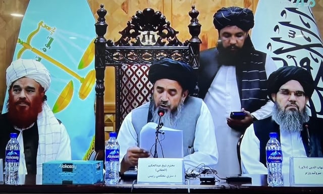 El presidente de la Corte Suprema afgana, Abdul Hakim Haqqani (c), detrás las banderas de la &#34;sharía&#34; y del nuevo gobierno talibán