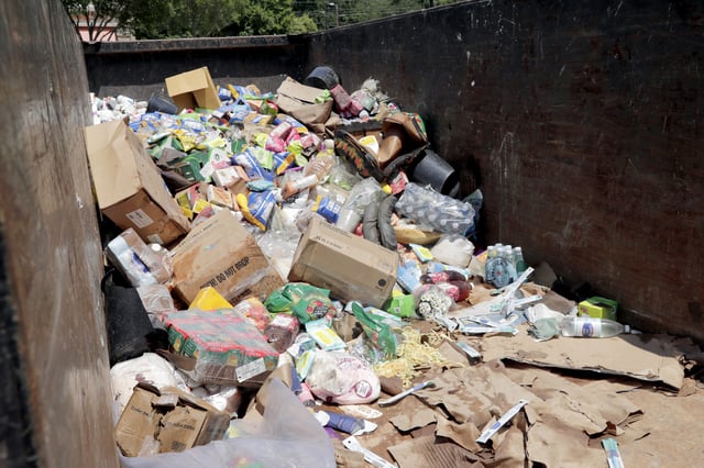 Damaged merchandise accumulates in a large dumpster at the Trader Joe's supermarket in the Eastgate shopping center after it was flooded out during tropical storm Chantal, Monday, July 7, 2025, in Chapel Hill, N.C. (AP Photo/Chris Seward)