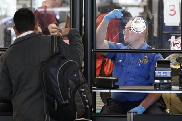 Un agente de la Administración de Seguridad en el Transporte (TSA) le hace señas al siguiente pasajero de una aerolínea en la fila en un control de seguridad en el Aeropuerto Internacional O&#39;Hare de Chicago, el viernes 26 de mayo de 2023