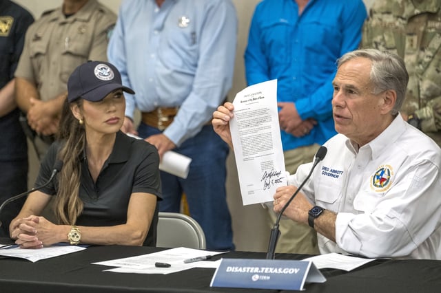 Texas Gov. Greg Abbott signs and holds up an disaster declaration proclamation as Homeland Security Secretary Kristi Noem, left, looks on during a press conference about recent flooding along the Guadalupe River, Saturday, July 5, 2025, in Kerrville, Texas.