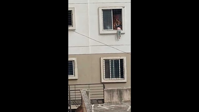 Leaning out of the bedroom window, the girl reportedly slipped and got stuck between the metal grill and the ledge, dangling dangerously several feet above the ground. (VIDEO GRAB)