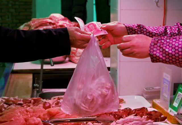 A man pays for meat at a market in Beijing, China January 11, 2021. REUTERS/Tingshu Wang/File Photo