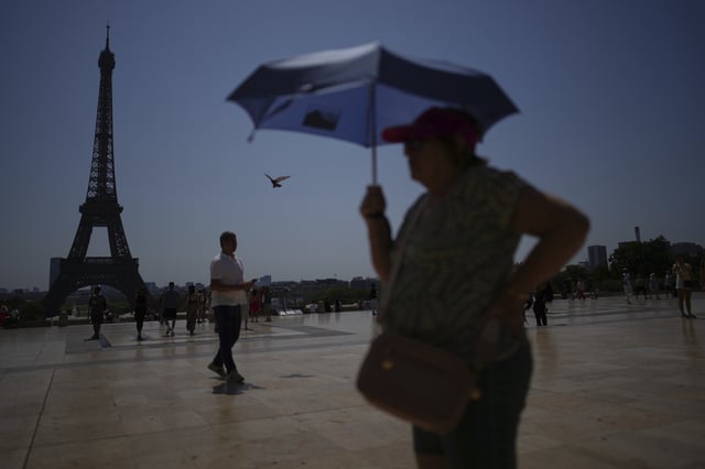 FILE - People walk at Trocadero plaza near the Eiffel Tower during a heat wave July 2, 2025, in Paris. (AP Photo/Christophe Ena, File)