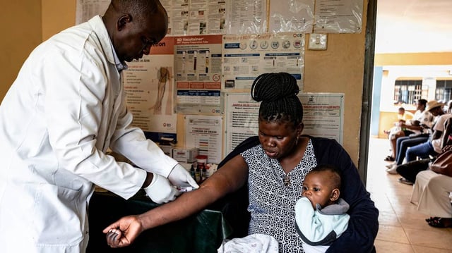 Martin Agunda (left), a lab technician at Kuoyo Sub-county Hospital, once supported by USAID, in Kisumu, prepares to test a viral load sample from Ruth Gweyi (right), a mother living with HIV on April 24, 2025, in Kisumu, Kenya. Kisumu has one of the highest HIV rates in Kenya, with around 17.6% of the adult population are living with the virus, nearly five times the national average of 4.5%. In 2025, Kisumu has beco