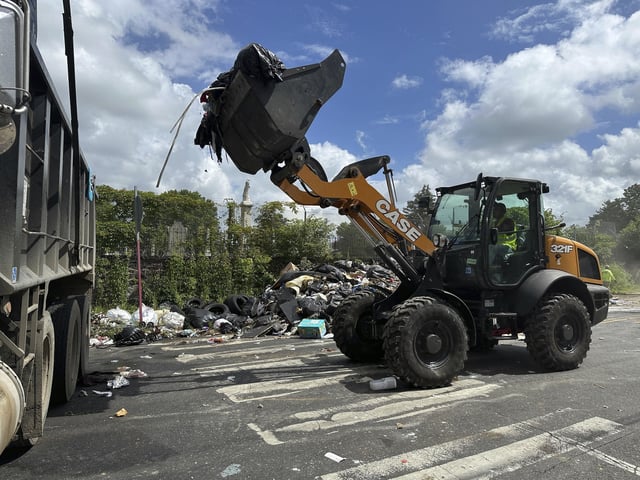 Trash is cleaned up at a drop-off site in Philadelphia as thousands of city workers remained on strike Monday, July 7, 2025. (AP Photo/Tassanee Vejpongsa)