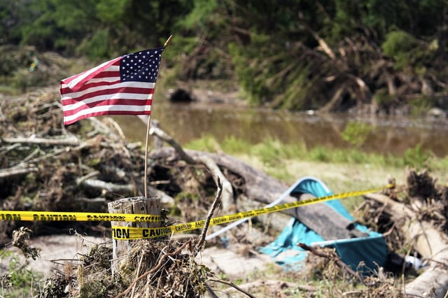 An American flag placed on a stump flies in Kerrville, Texas on Tuesday, July 8, 2025.