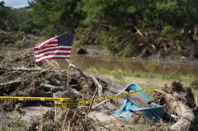 An American flag placed on a stump flies in Kerrville, Texas on Tuesday, July 8, 2025. (AP Photo/Ashley Landis)