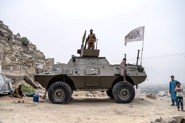 A Taliban security personnel stands over an armoured tank bearing a Taliban flag, as he keeps guard during a religious procession by Afghan Shiite Muslims celebrating Ashura, on the tenth day of the Islamic holy month of Muharram, in Kabul on July 6, 2025.