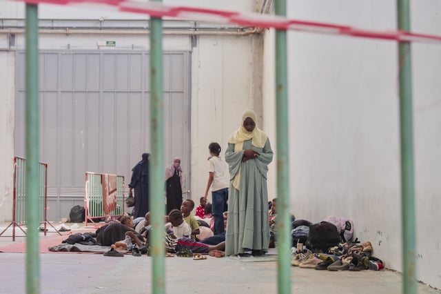 A woman prays as migrants from Africa rest in Agia port, Chania, Crete island, Greece, Monday, July 7, 2025. (AP Photo/Giannis Angelakis)