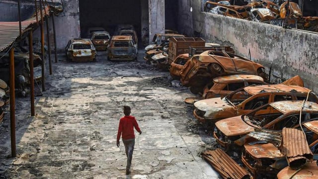 New Delhi: A man walks past the charred remains of vehicles set ablaze by rioters at parking during the anti-CAA protests in February at Shiv Vihar area of Northeast Delhi (PTI)