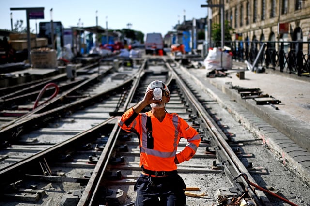A labourer drinks water to cool down as he works on a construction site of tramway lines along the Garonne river during a heatwave in Bordeaux, south-western France on July 1, 2025.