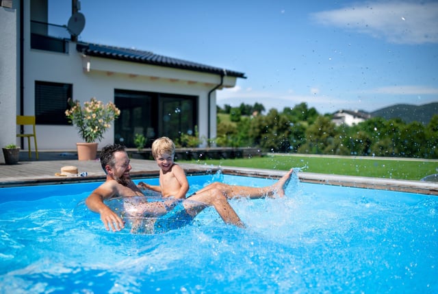 Man with son having fun in hot summer garden.