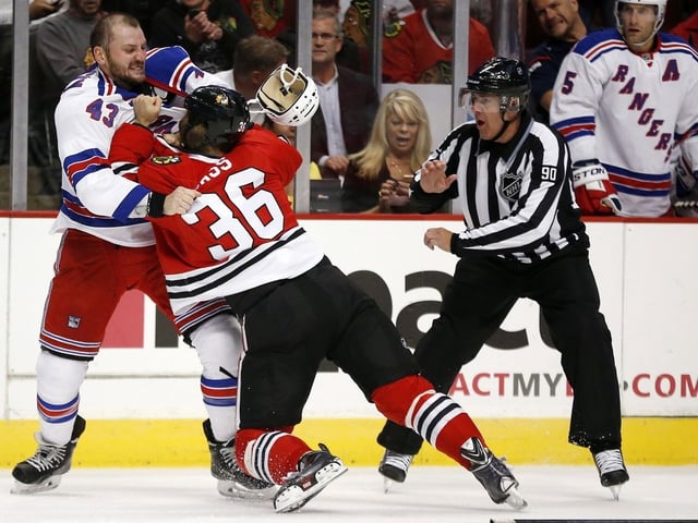 New York Rangers forward Nick Tarnasky (43) and Chicago Blackhawks centre Cody Bass (36) fight as linesman Andy McElman looks on during the first period of a preseason NHL hockey game on Friday, Sept. 26, 2014, in Chicago.