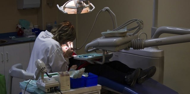 A dentist works on a patient at a public health clinic in Madrid March 27, 2012. Spain will announce some of its deepest budget cuts ever on Friday, though evaporating growth prospects mean it is likely to fall short of what is needed to meet strict public deficit targets. Picture taken March 27, 2012. REUTERS/Sergio Perez  (SPAIN - Tags: HEALTH BUSINESS POLITICS) españa madrid  españa consultorio odontologico dentista dentistas