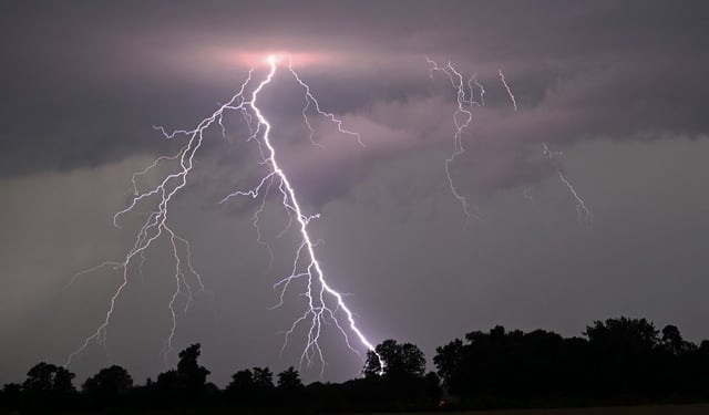 TOPSHOT - Lightning strikes over the countryside during a thunderstorm following high temperatures on July 10, 2024 near Potsdam, eastern Germany. (Photo by RALF HIRSCHBERGER / AFP) (Photo by RALF HIRSCHBERGER/AFP via Getty Images)
