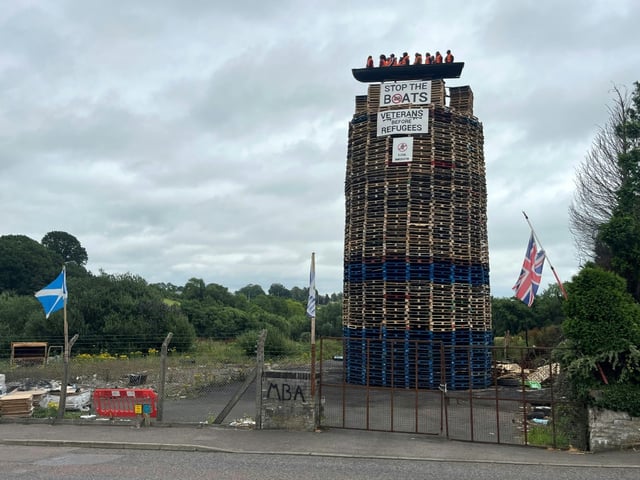 An effigy of migrants aboard a boat was placed atop a tower due to be set alight in Northern Ireland, drawing criticism